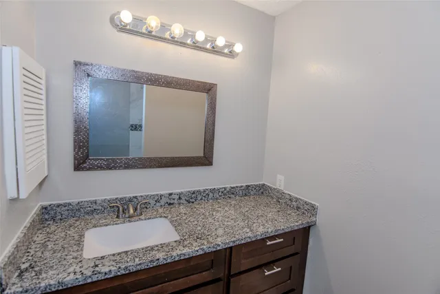 a bathroom with a granite countertop sink and a mirror