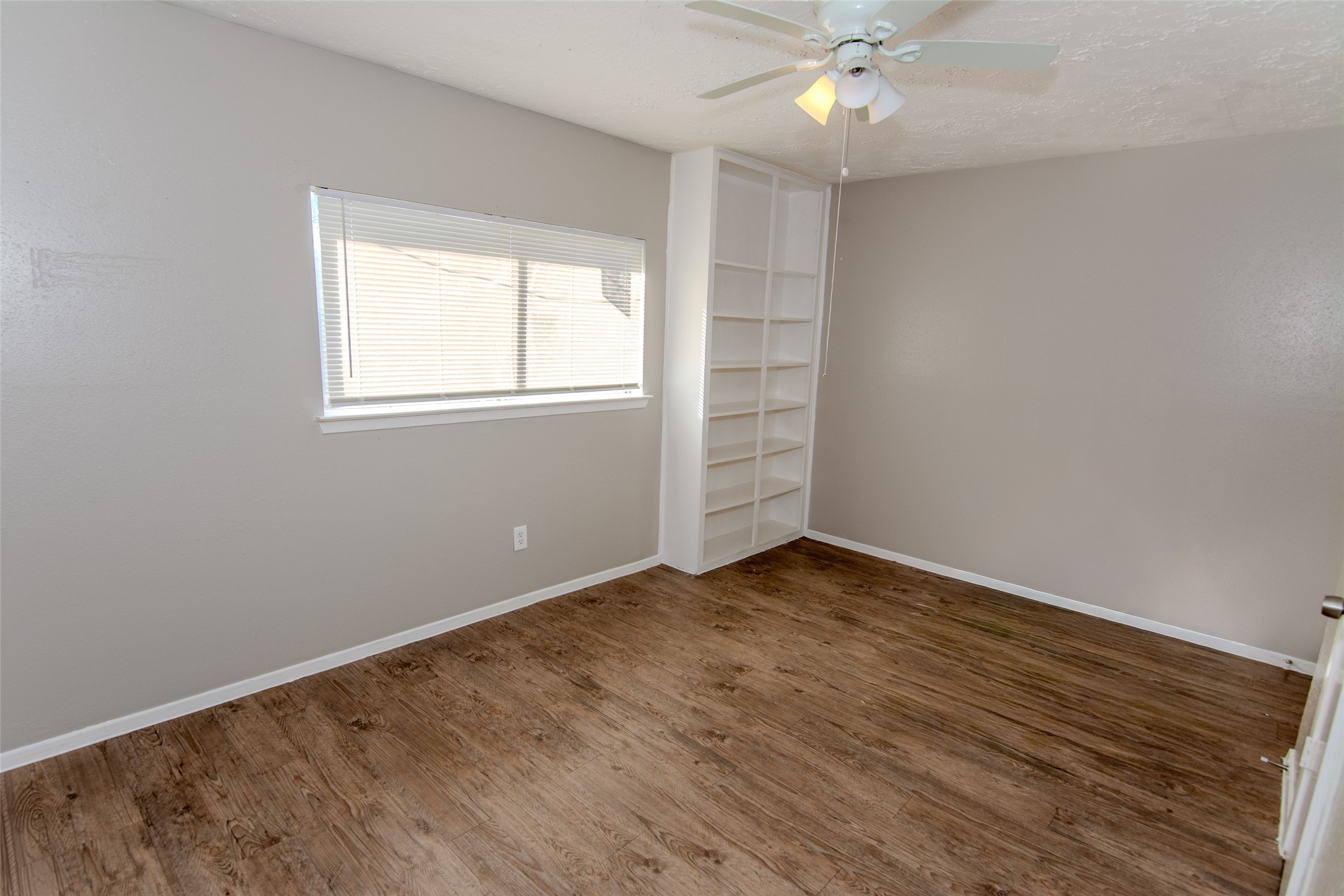 20031 Woodhall Lane Humble, TX 77338 - Photo 15 of 16 an empty room with wooden floor chandelier fan and windows