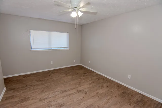 an empty room with a window and a fan