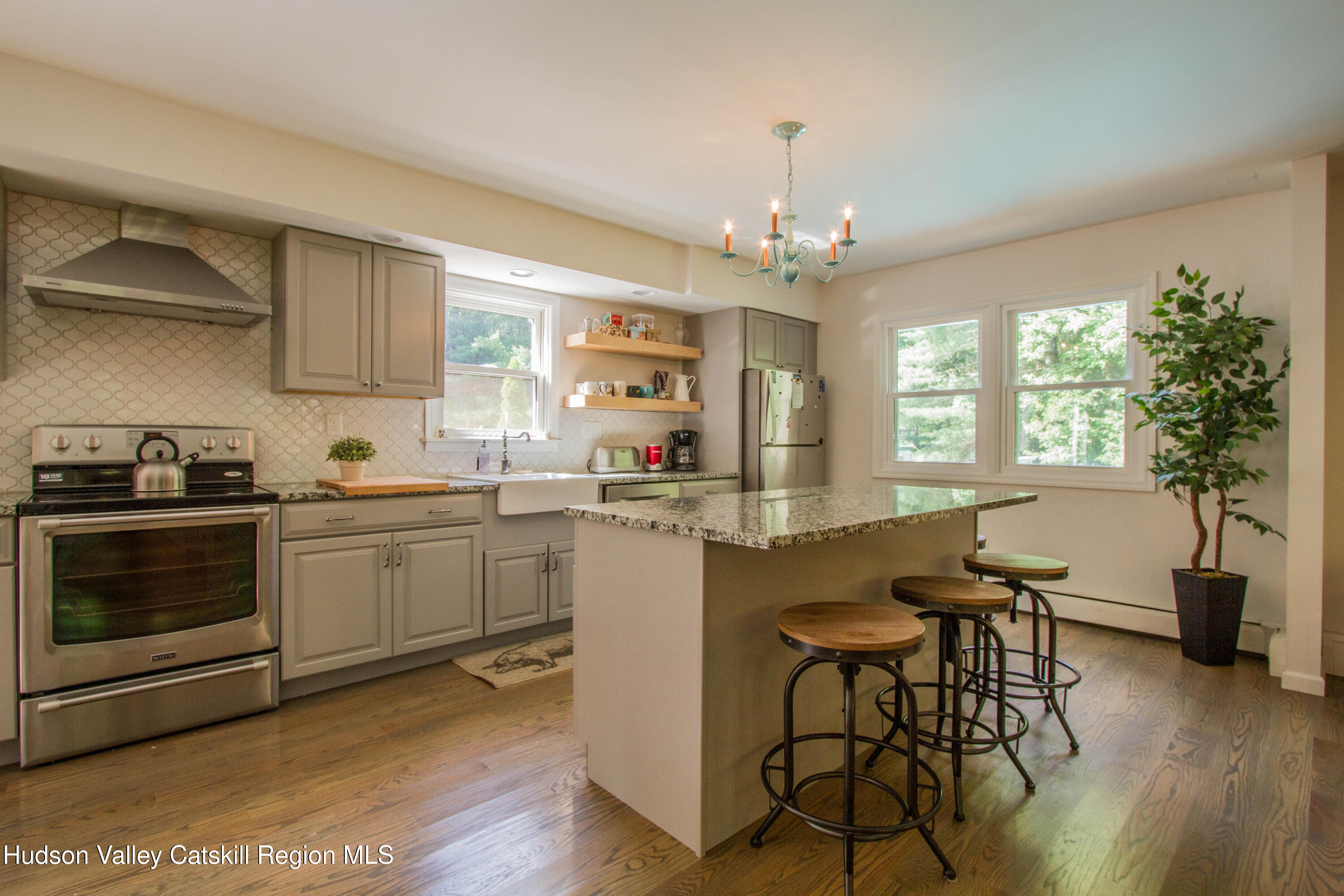 11 Shultis Farm Road Woodstock, NY 12409 - Photo 6 of 23 a kitchen with kitchen island granite countertop a stove a sink a dining table and chairs with wooden floor