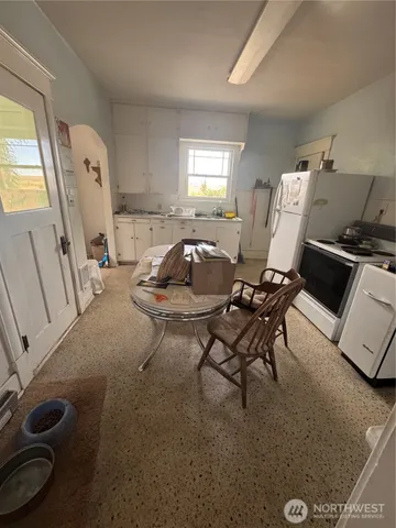 a large kitchen with kitchen island granite countertop a stove a sink a dining table and chairs with wooden floor