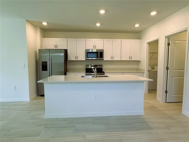 a kitchen with stainless steel appliances granite countertop a stove a sink and a refrigerator