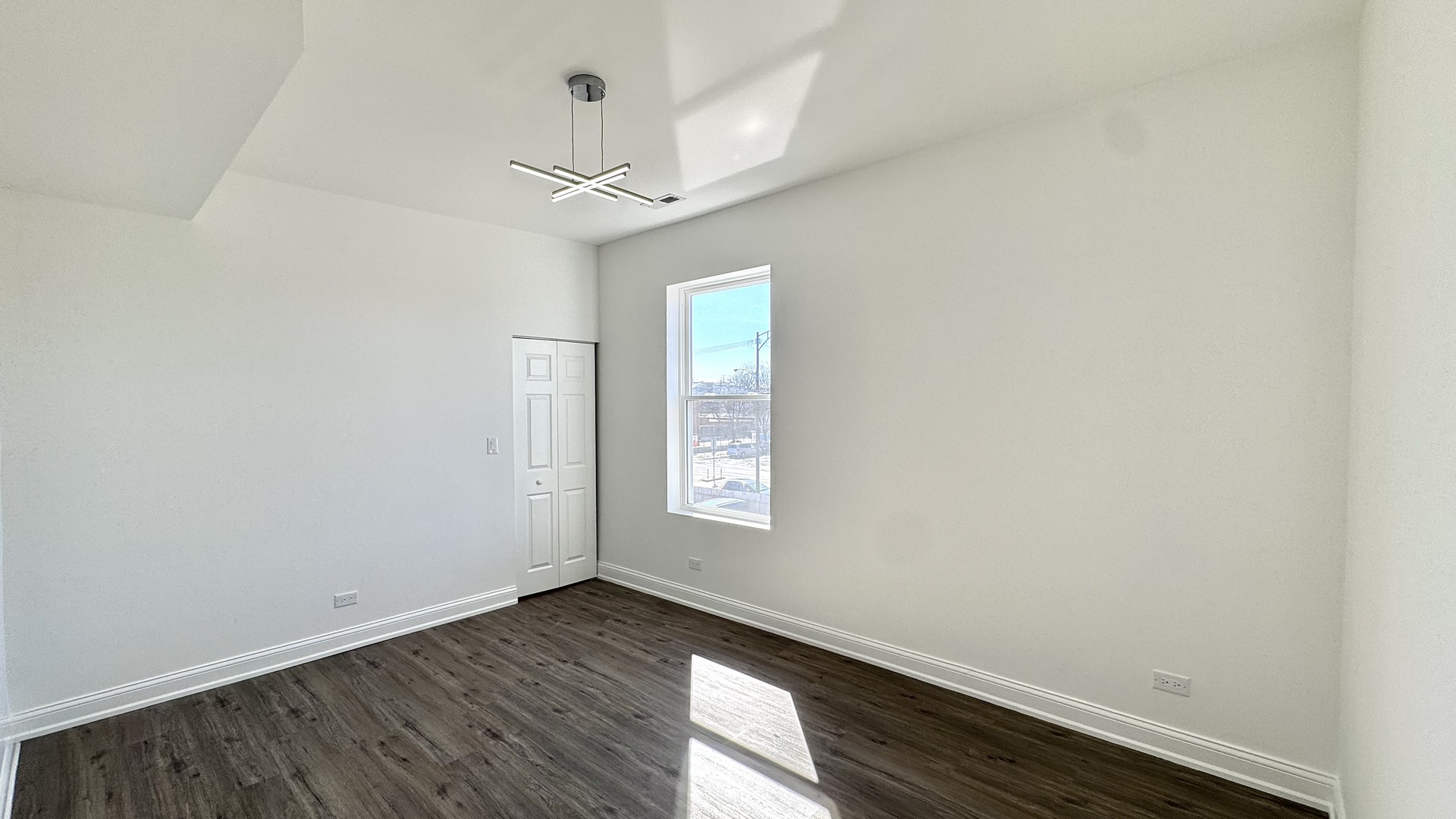 4751 West Monroe Street Chicago, IL 60644 - Photo 8 of 22 an empty room with wooden floor chandelier fan and windows