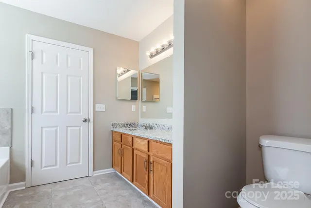 a bathroom with a granite countertop toilet sink and mirror