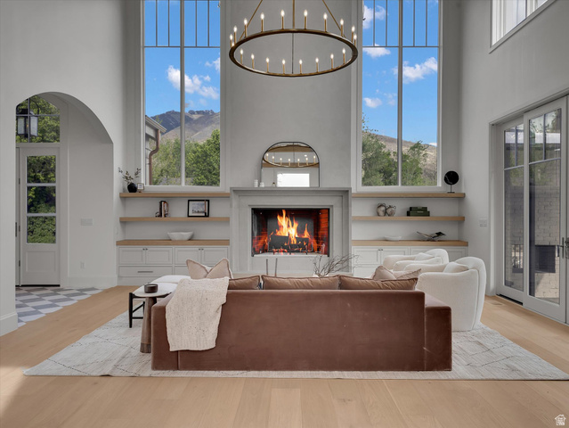 13216 Telemark Lane Draper, UT 84020 - Photo 4 of 41 Living room featuring a high ceiling, a lit fireplace, light wood-type flooring, a mountain view, and arched walkways