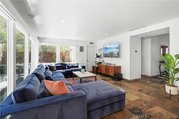a living room with furniture floor to ceiling window and potted plants