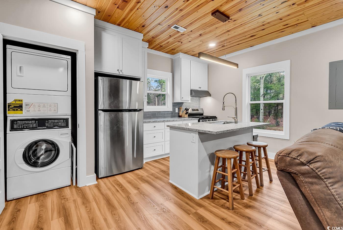 32 Old Place Kingstree, SC 29556 - Photo 37 of 40 Kitchen featuring stainless steel appliances, wood ceiling, a breakfast bar area, stacked washing machine and dryer, and light stone counters