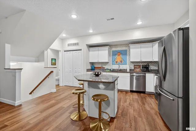 a kitchen with a refrigerator a sink dishwasher a stove and white cabinets with wooden floor