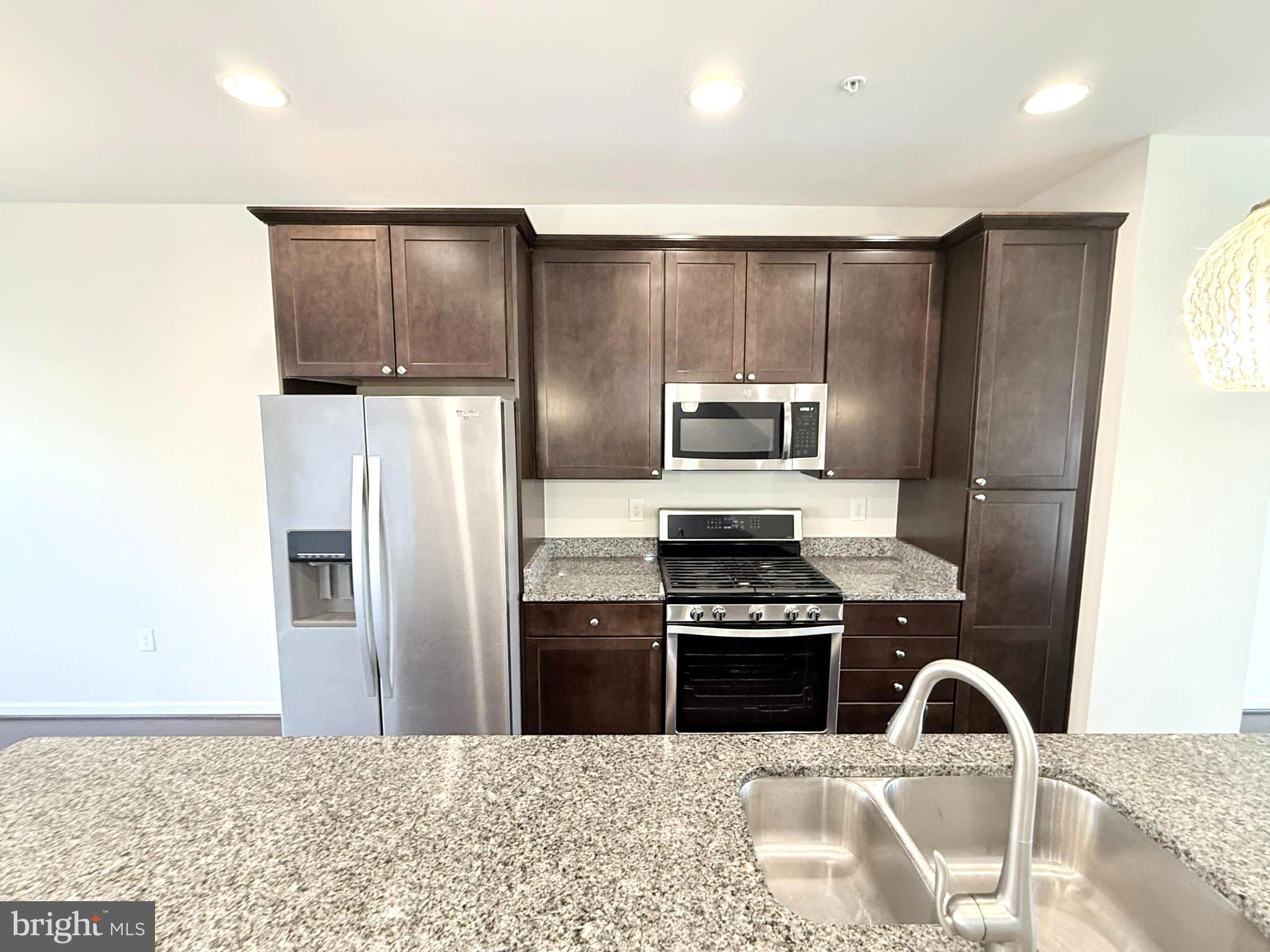 6082 Forum Square Frederick, MD 21703 - Photo 22 of 63 a kitchen with granite countertop a refrigerator and a stove top oven