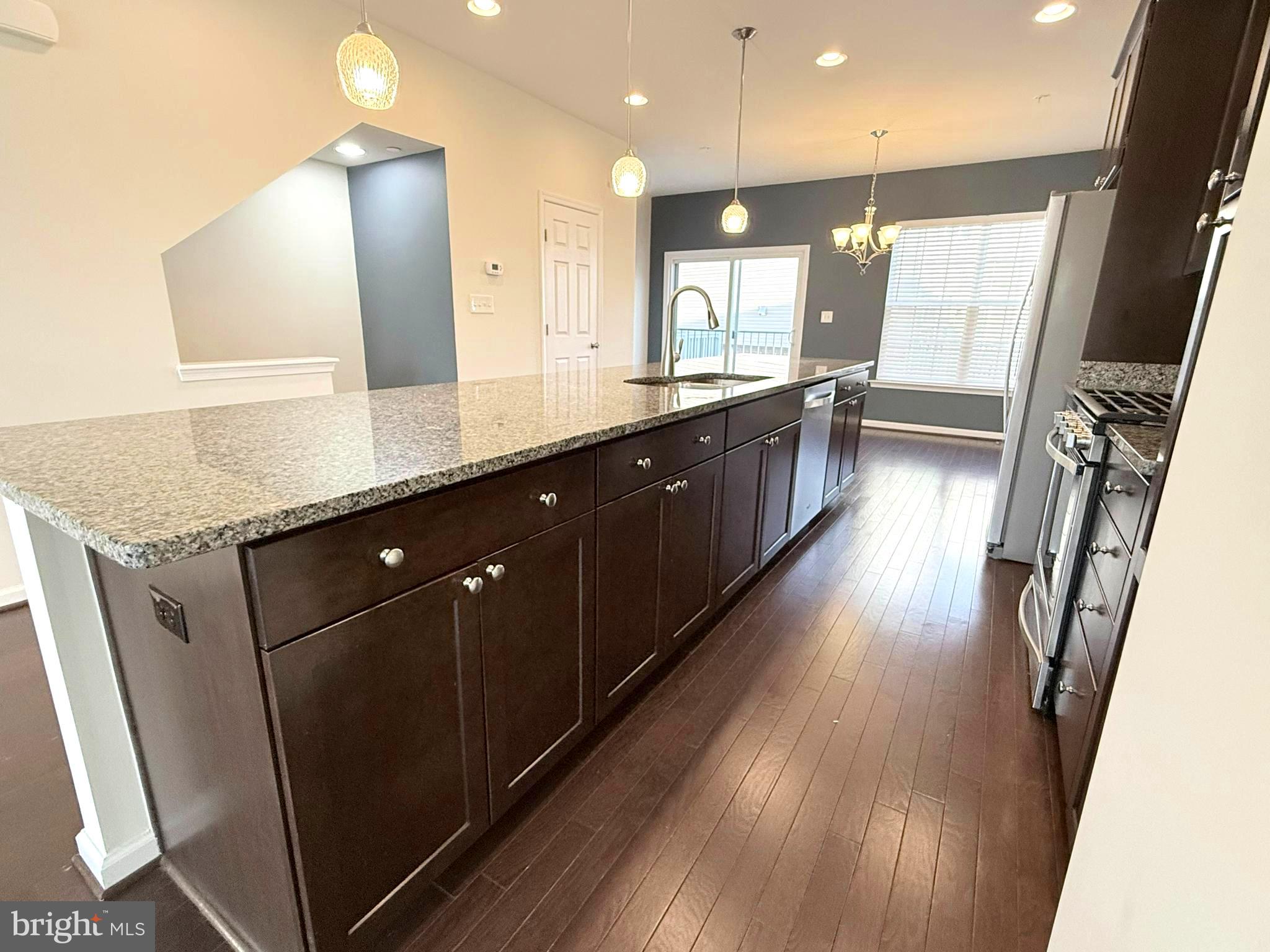 6082 Forum Square Frederick, MD 21703 - Photo 24 of 63 a open kitchen with stainless steel appliances granite countertop a refrigerator a sink dishwasher a stove and white countertops with wooden floor