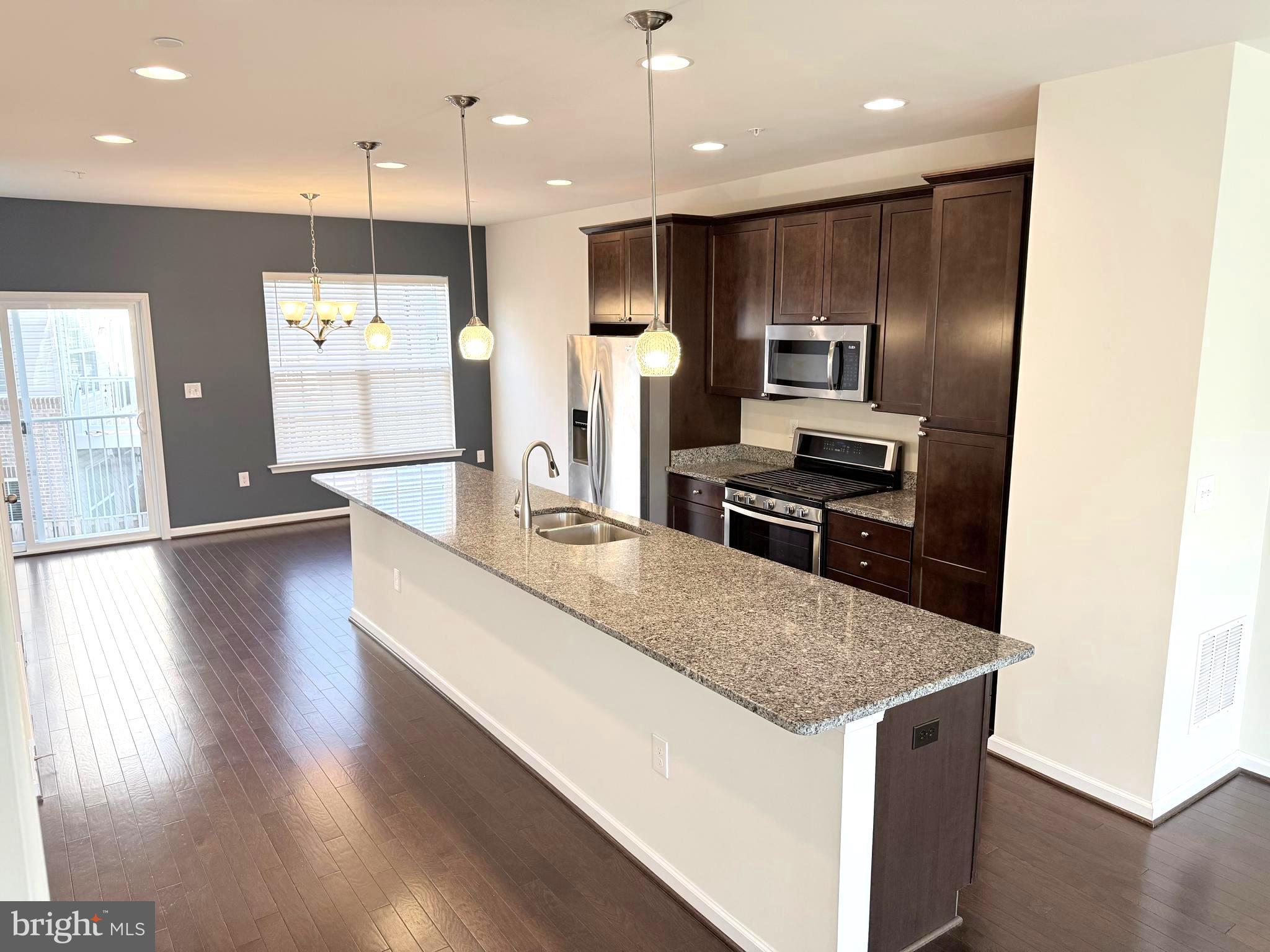 6082 Forum Square Frederick, MD 21703 - Photo 27 of 63 a kitchen with kitchen island a refrigerator and a stove top oven