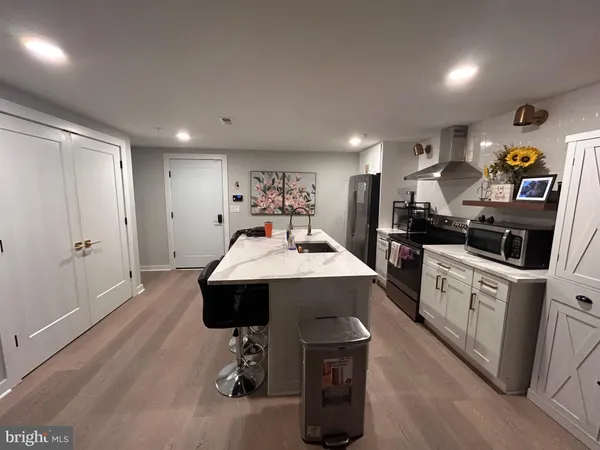 a kitchen with stainless steel appliances a sink a stove a refrigerator cabinets and living room view