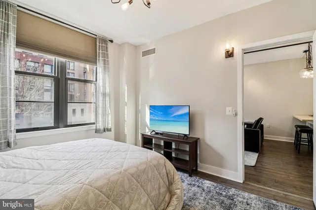 a bedroom with a bed and a dresser with wooden floor