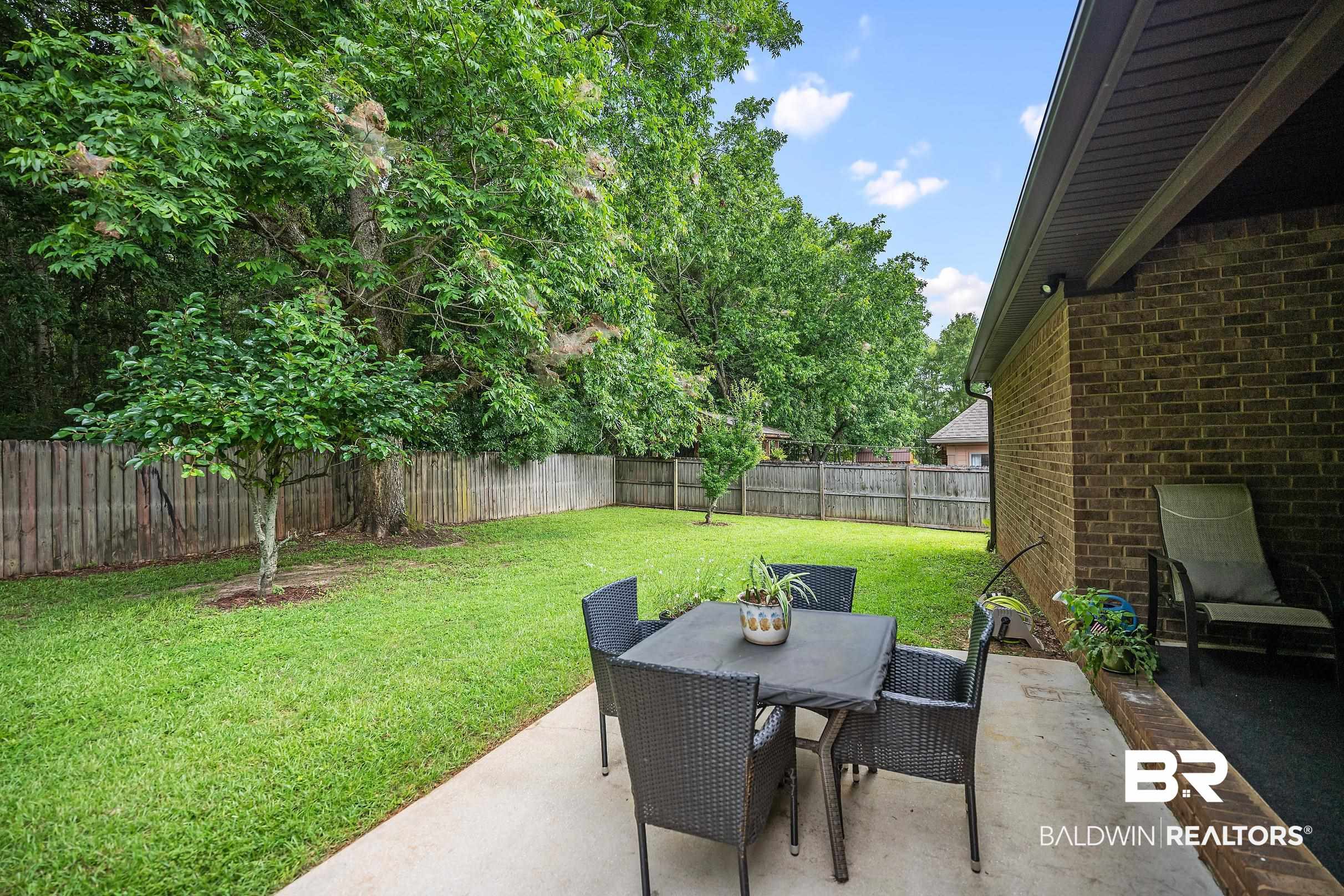 313 Pecan Ridge Boulevard Fairhope, AL 36532 - Photo 38 of 51 Expansive backyard featuring a lush lawn, mature trees, and a full perimeter wood fence