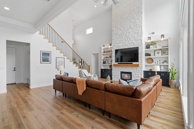 2278 Tawny Ridge Circle St. George, UT 84790 - Photo 8 of 61 Vaulted ceiling living area featuring a floor-to-ceiling stone-clad fireplace with wood mantel, built-in shelving, wood-finish flooring, and a staircase with black metal balusters.