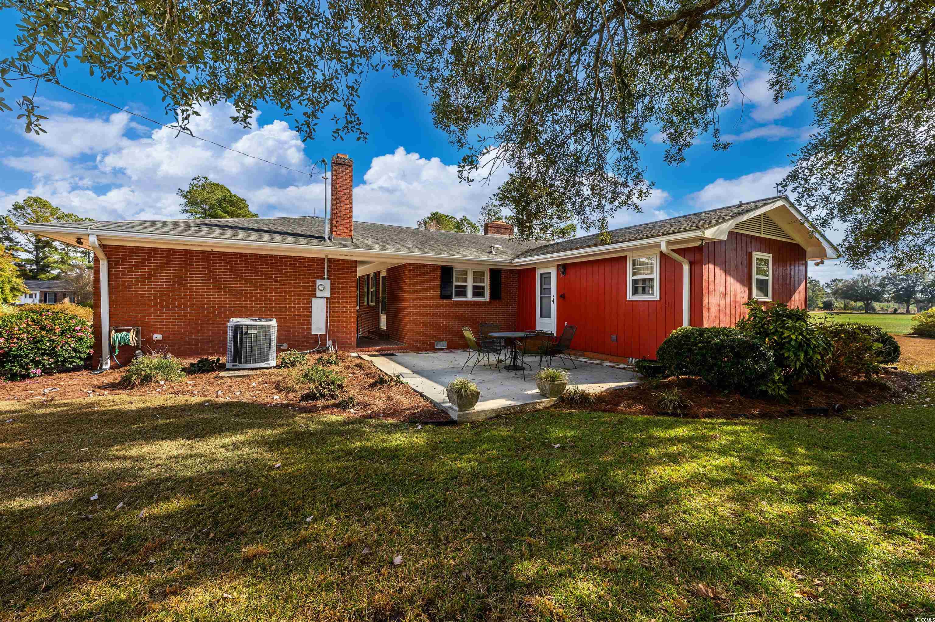 1870 Highway 348 Loris, SC 29569 - Photo 24 of 34 Back of property with a patio, a chimney, a lawn, and brick siding