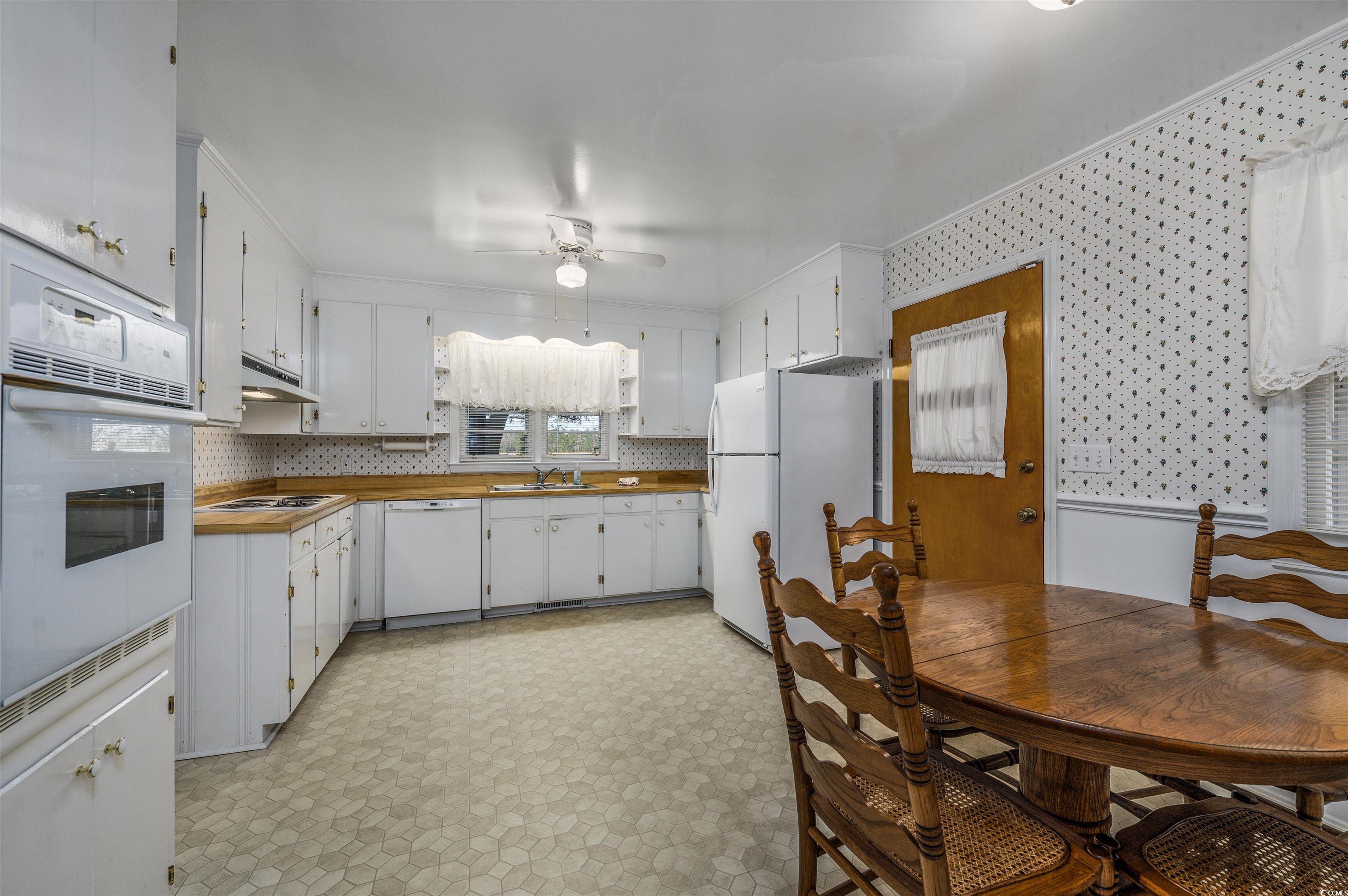 1870 Highway 348 Loris, SC 29569 - Photo 8 of 34 Kitchen featuring light floors, white appliances, white cabinetry, ceiling fan, and wallpapered walls