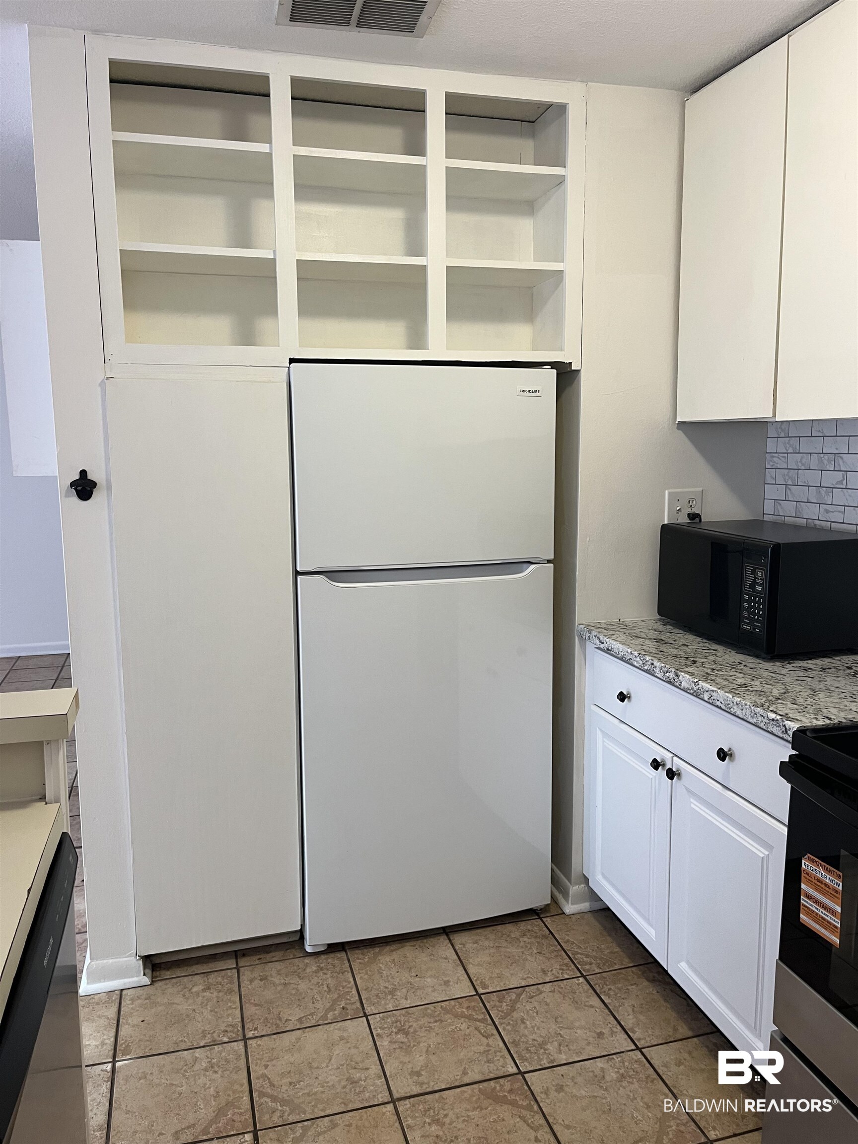 1146 North Alston Street Foley, AL 36535 - Photo 11 of 20 Kitchen featuring electric range, freestanding refrigerator, black microwave, white cabinetry, and decorative backsplash