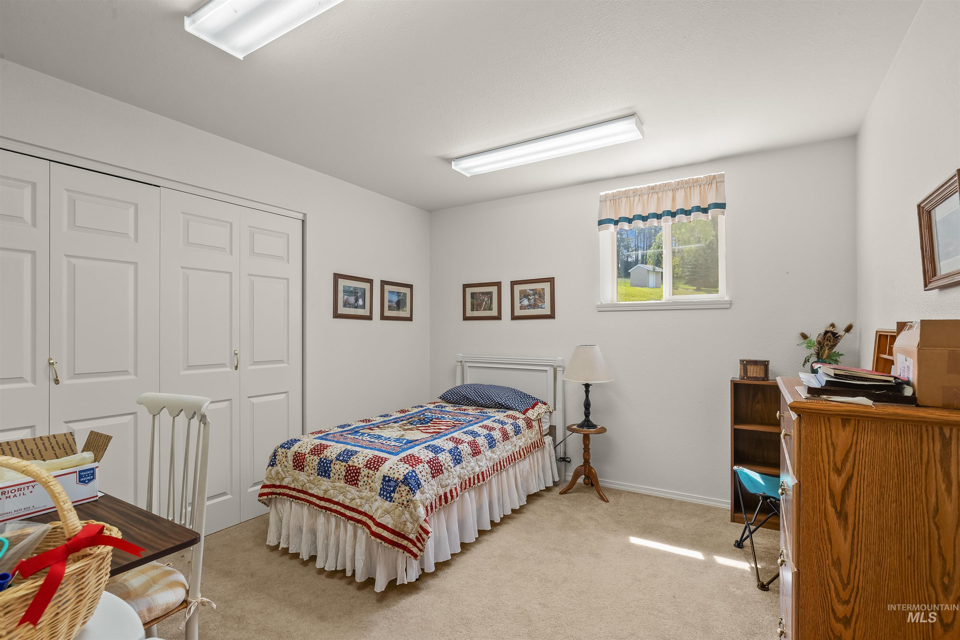 743 Wall Crk Road Stites, ID 83552 - Photo 36 of 48 Bedroom featuring a window with a valance, light beige carpeting, white walls, and a closet with bifold doors