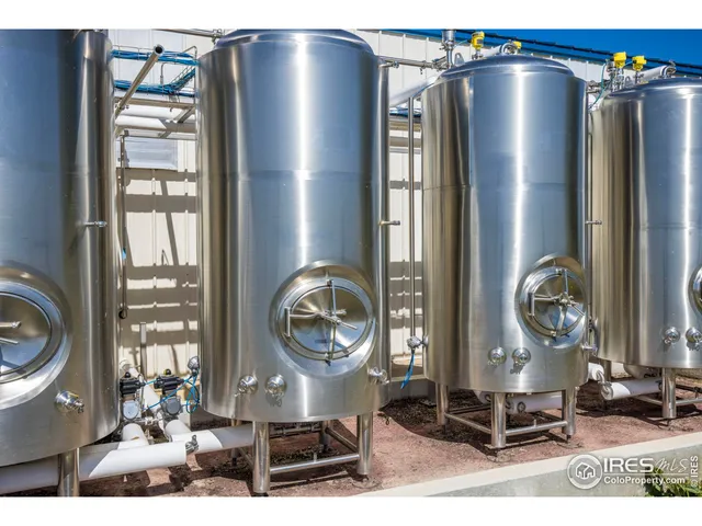 a living room with stainless steel appliances kitchen island granite countertop a refrigerator a stove and a wooden floor