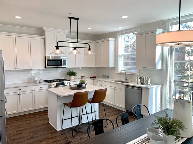 a kitchen with stainless steel appliances granite countertop a stove top oven a sink dishwasher a dining table and chairs with wooden floor