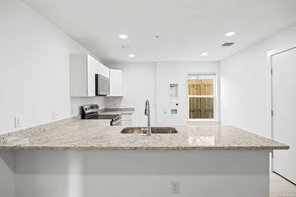 a kitchen with granite countertop white cabinets and appliances