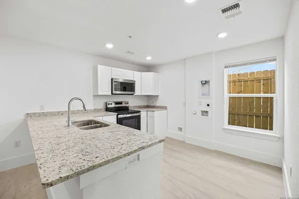 a kitchen with granite countertop white cabinets and white appliances