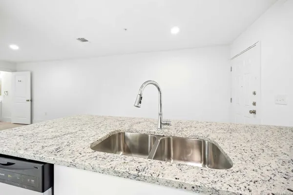 a kitchen with granite countertop white cabinets and stainless steel appliances