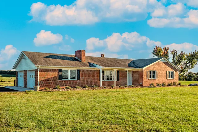 a front view of house with yard and trees in the background