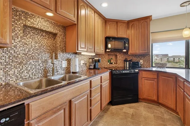 a kitchen with kitchen island granite countertop a sink dishwasher stove and cabinets