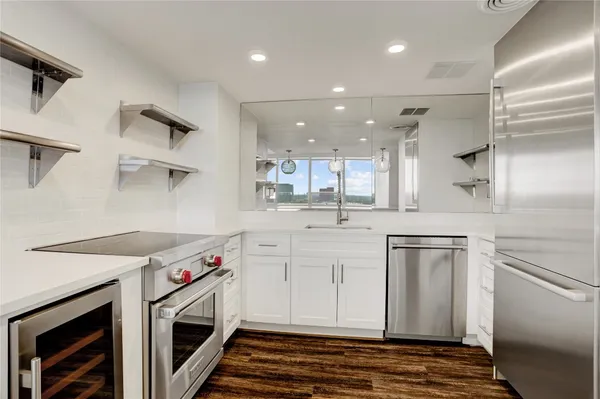 a kitchen with stainless steel appliances granite countertop a sink a stove and a refrigerator