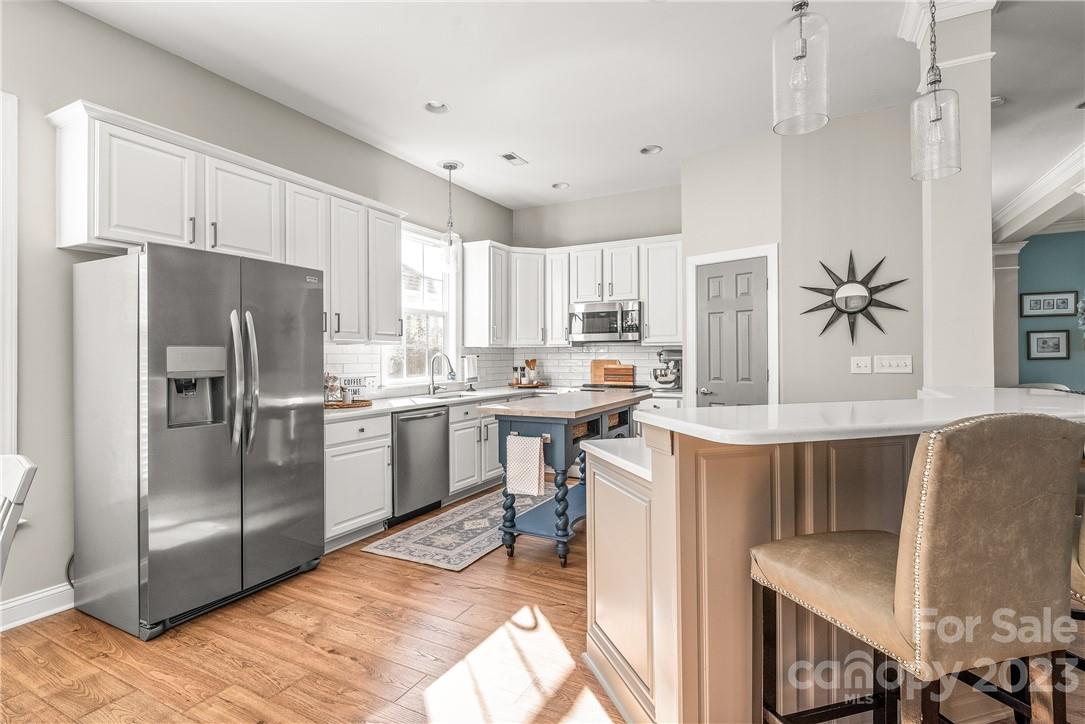 4108 Cedar Point Avenue Matthews, NC 28104 - Photo 13 of 41 a kitchen with kitchen island a refrigerator a stove a sink and white cabinets