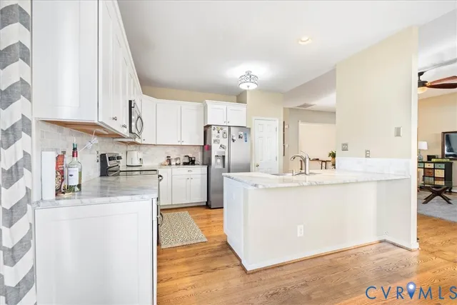 a kitchen with stainless steel appliances a sink a stove a refrigerator cabinets and a window