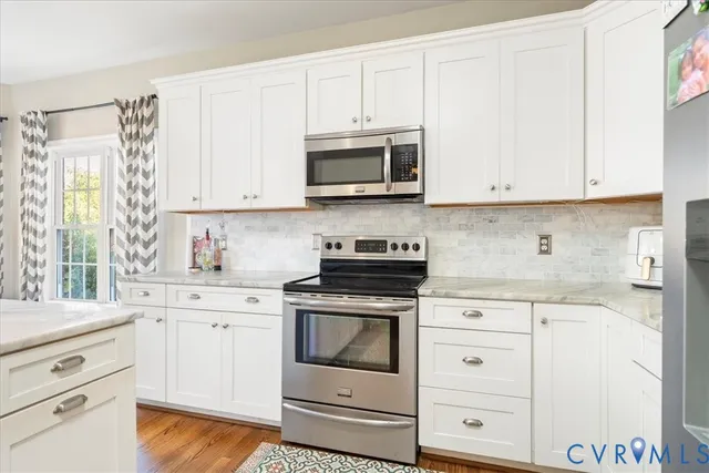 a kitchen with stainless steel appliances granite countertop white cabinets and a stove a oven with white countertops
