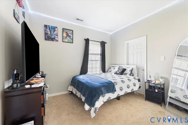 a bedroom with a bed and a flat tv screen on dresser