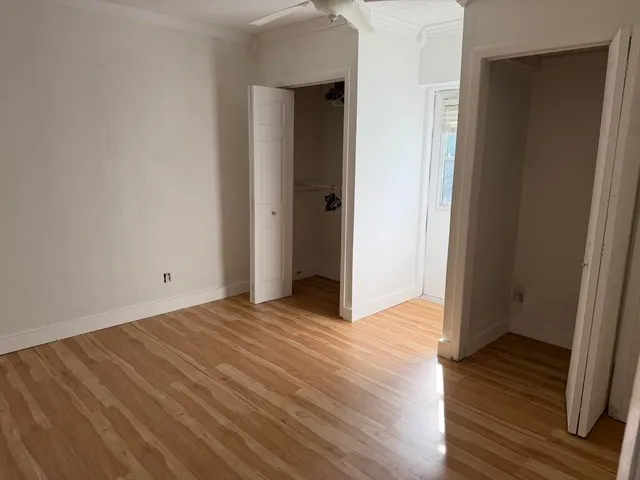 a view of an empty room with wooden floor and closet