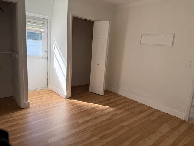 an empty room with wooden floor and entrance