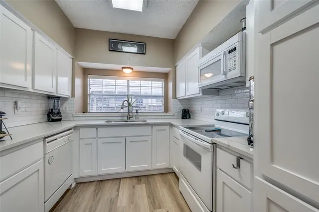 a kitchen with granite countertop white cabinets and white appliances
