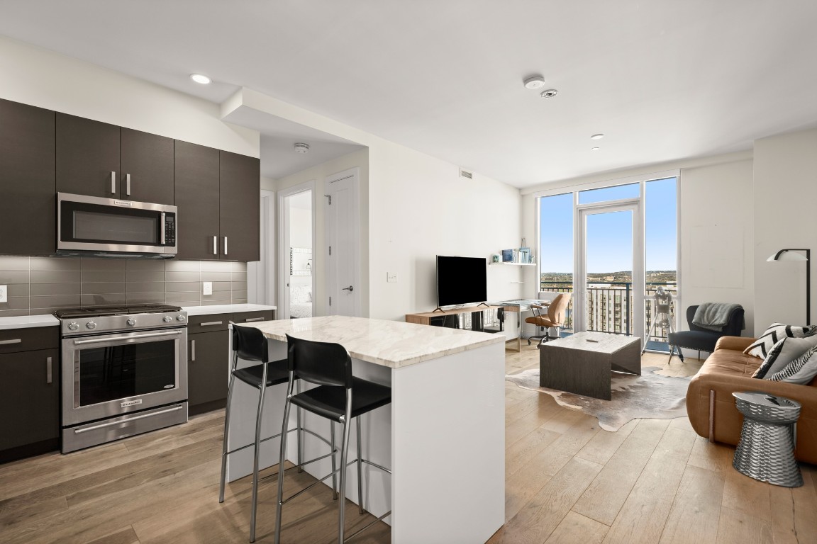 222 West Avenue, Unit 2012 Austin, TX 78701 - Photo 37 of 37 a kitchen with stainless steel appliances a stove top oven a sink dishwasher a dining table and chairs with wooden floor