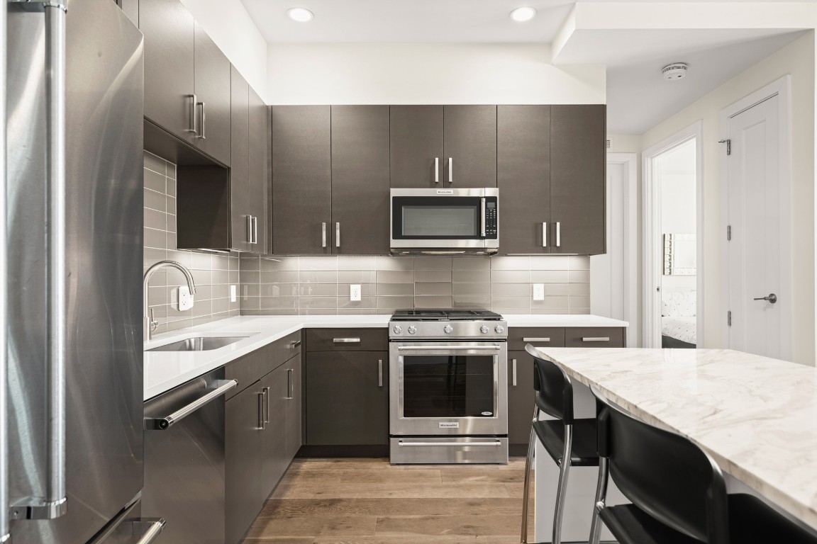222 West Avenue, Unit 2012 Austin, TX 78701 - Photo 2 of 37 a kitchen with stainless steel appliances granite countertop a stove top oven a sink and dishwasher a refrigerator with wooden floor
