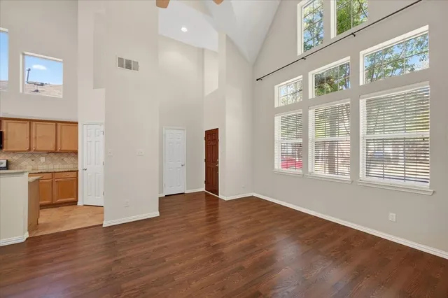 a view of an empty room with a window and wooden floor