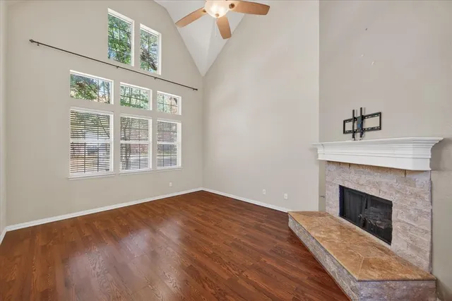 a view of an empty room with wooden floor fireplace and a window