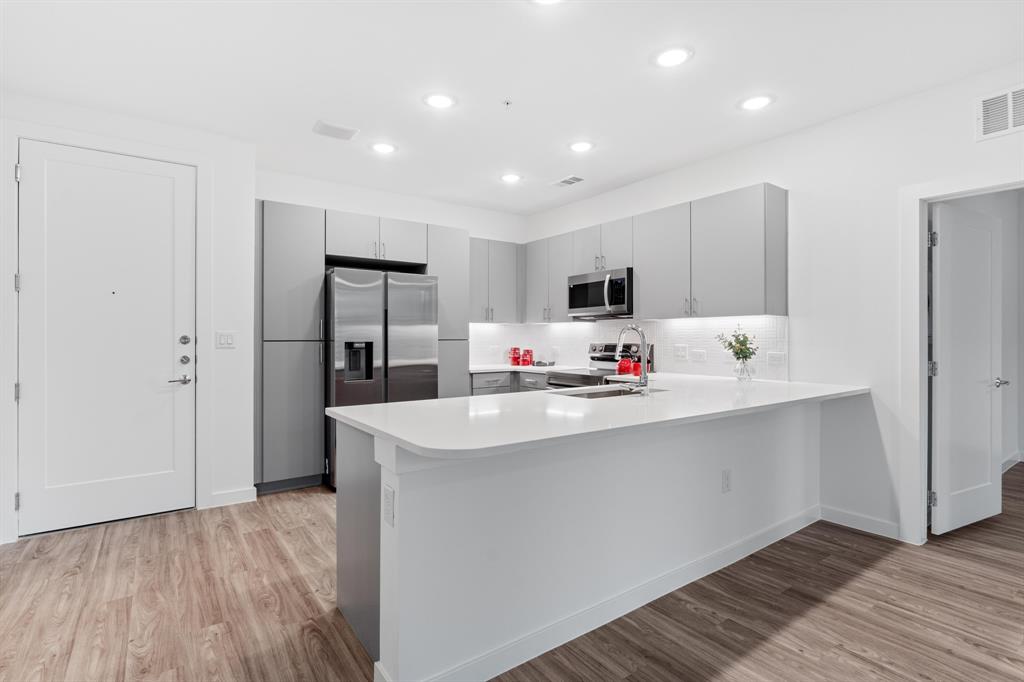 4801 Springdale Road, Unit 2010 Austin, TX 78723 - Photo 6 of 28 Kitchen featuring a peninsula, gray cabinetry, light wood-style floors, stainless steel appliances, and recessed lighting