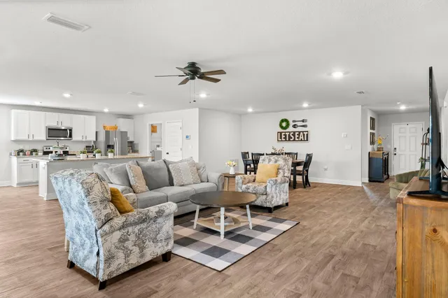 a living room with furniture kitchen view and a chandelier
