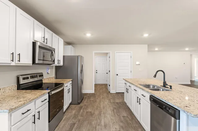 a kitchen with granite countertop a sink refrigerator and cabinets
