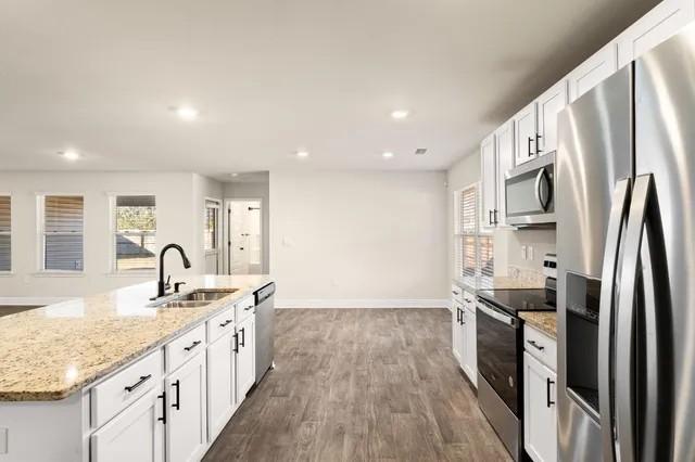 a large kitchen with stainless steel appliances a large counter top and a stove top oven