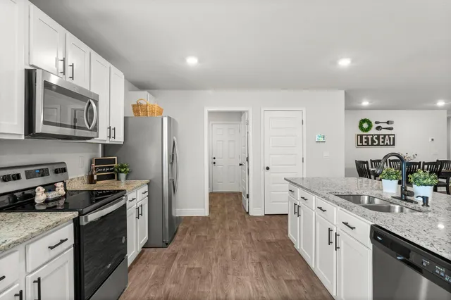 a kitchen with granite countertop a sink stove refrigerator and cabinets