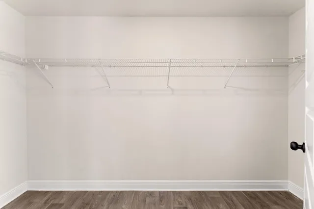 an empty room with wooden floor chandelier fan and windows