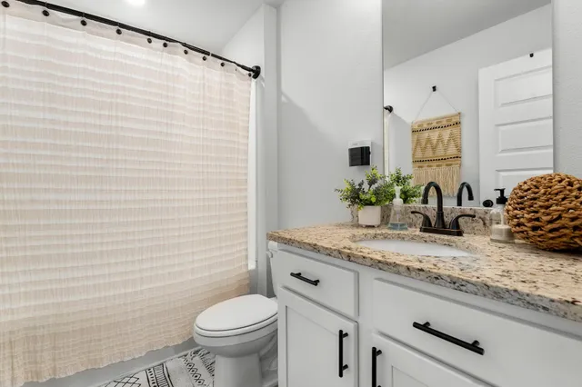 a bathroom with a granite countertop sink a toilet and a mirror