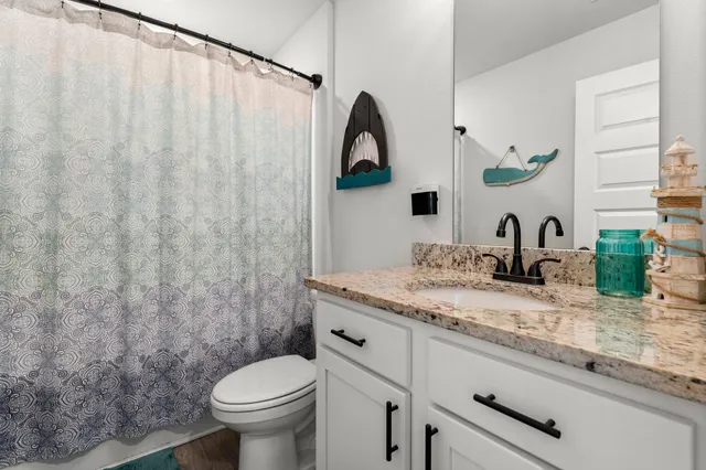 a bathroom with a granite countertop sink toilet and a mirror